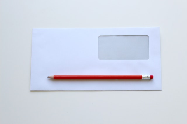 a blank envelope with a red pencil on top